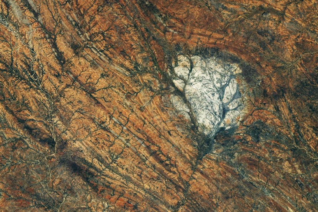 NASA astronaut photograph of southern Madagascar, showing a pale, rounded rock outcrop among darker, reddish terrain crossed by long linear patterns.